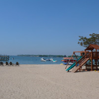 Beach with Playground Equipment and Sail Boats in the Distance
